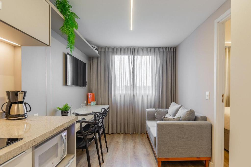 a kitchen and living room with a couch and a table at Easy Life Campos PUC by Xtay - Hospede-se próximo ao Viasoft Experience e Estádio Durival in Curitiba