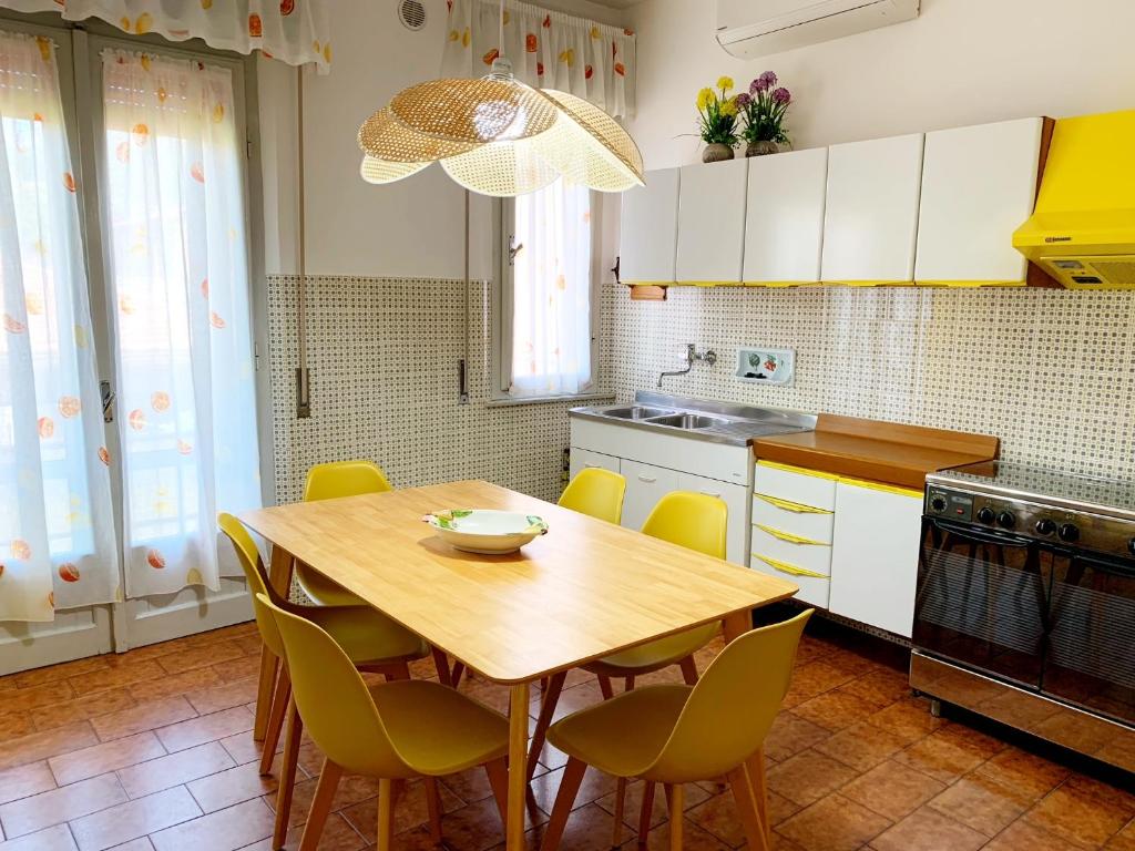 eine Küche mit einem Holztisch und gelben Stühlen in der Unterkunft Appartamenti Tina Paolini 2 con terrazzo in Castiglione della Pescaia