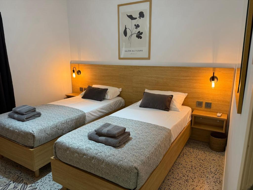 two beds in a hotel room with towels on them at Camelia - 3 Bedroom Apt with terrace and Seaviews - Bugibba Promanade in St Paul's Bay