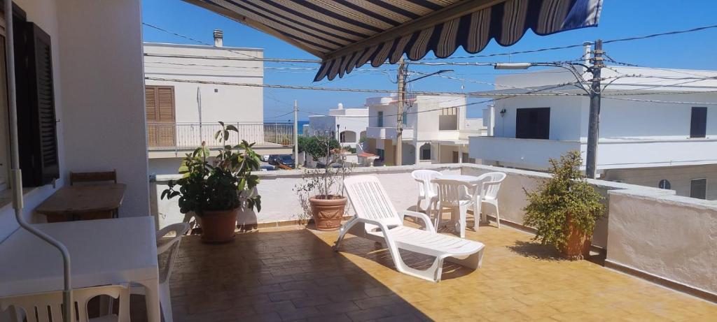 een patio met witte stoelen en tafels op een balkon bij Casa al mare in centro a 100 metri dalla spiaggia con terrazza in Torre Santa Sabina