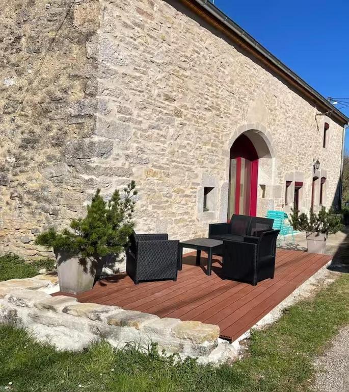 une terrasse en bois avec des chaises et une table devant un bâtiment dans l'établissement Le Nichoir des Lacs, au coeur du pays des Lacs, Jura, à Barésia-sur-lʼAin