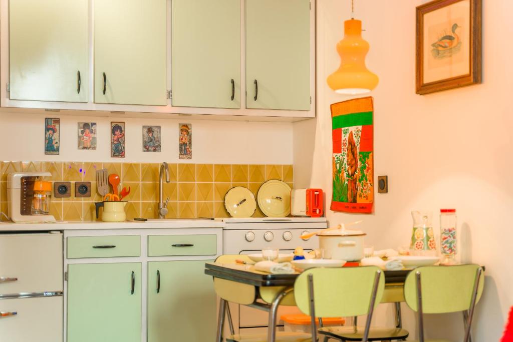 eine Küche mit weißen Schränken und einem Tisch mit Stühlen in der Unterkunft Les Seventies - Confort Vintage proche gare in Chambéry