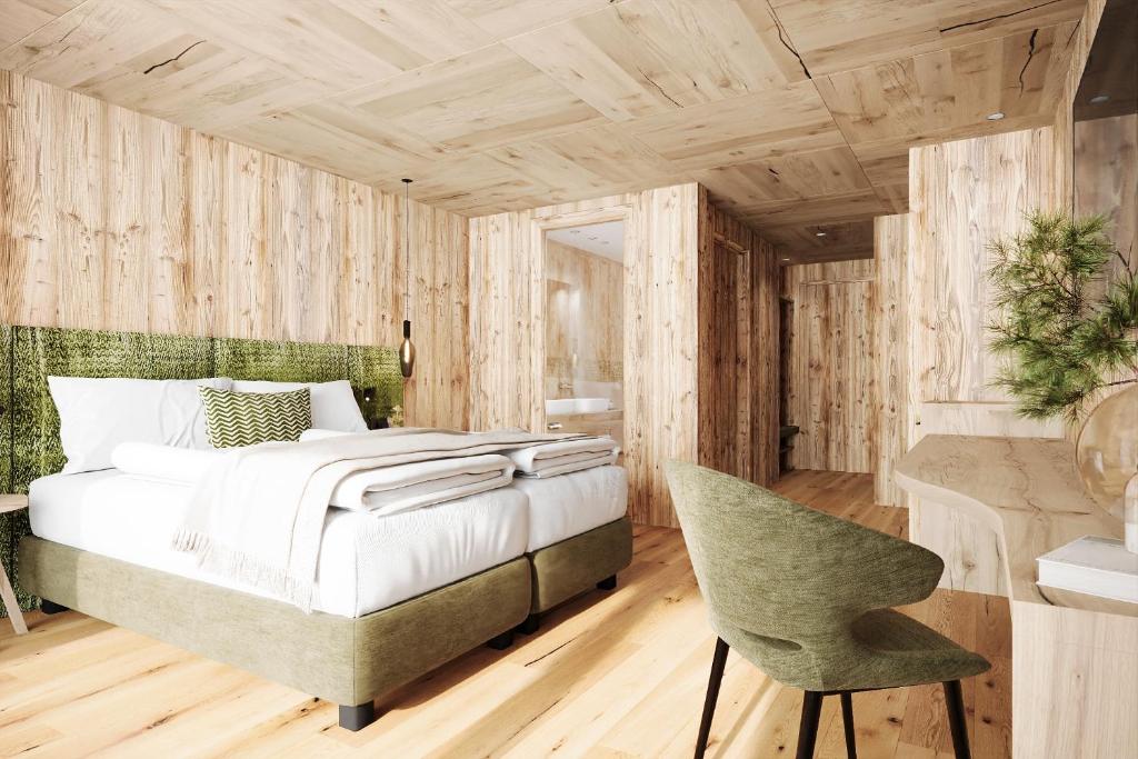 a bedroom with a bed and a chair at Luxury B&B August in Ortisei