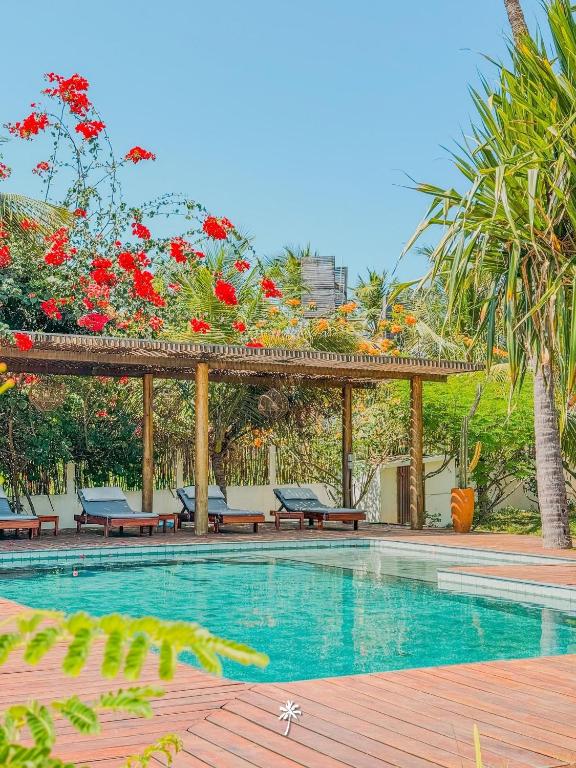 a swimming pool with a pergola with benches and flowers at Villa Guaiuba linda casa com piscina e vista por mar ! in Icaraí