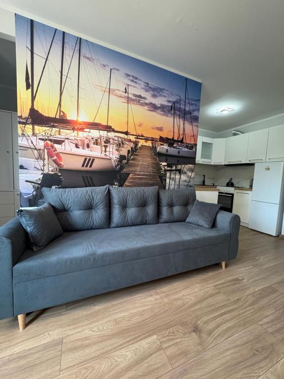 a living room with a couch and a painting of a harbor at Żeglarska przystań in Giżycko