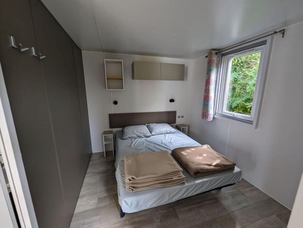 a small bedroom with a bed and a window at Camping de Lanven in Plomeur
