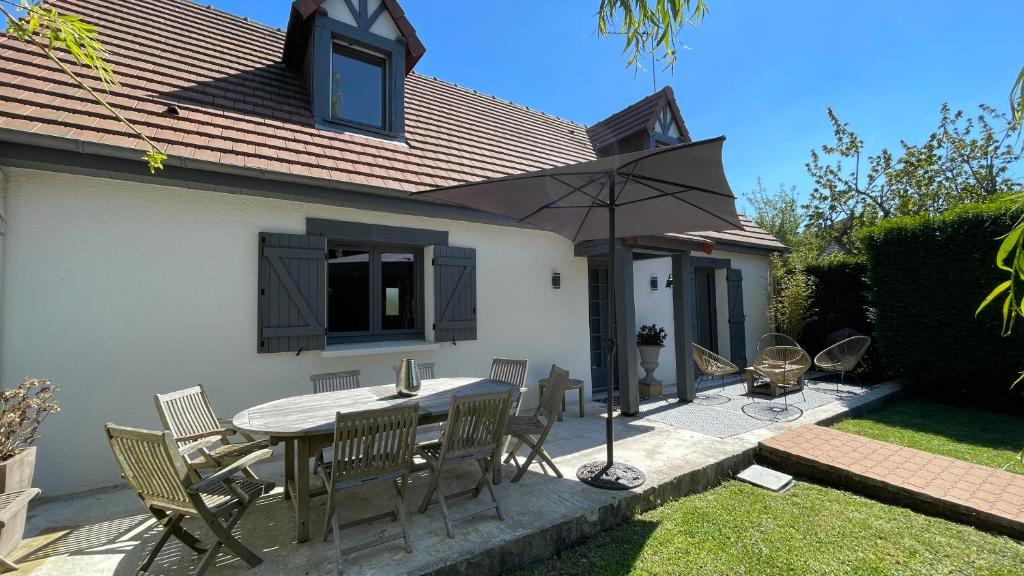 un patio avec une table, des chaises et un parasol dans l'établissement Mon Petit Cabourg, à Cabourg