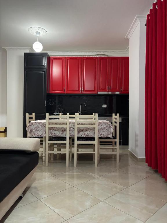 a dining room with red cabinets and a table and chairs at Chloe Beach Apartment in Lezhë