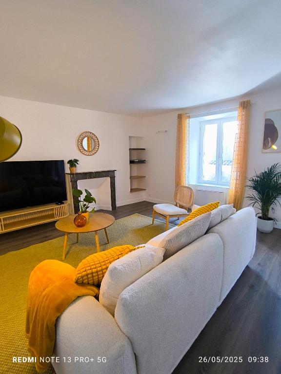 a living room with a couch and a tv at Le Gîte des Capucines - Cosy - 20mn du Parc in Mauléon