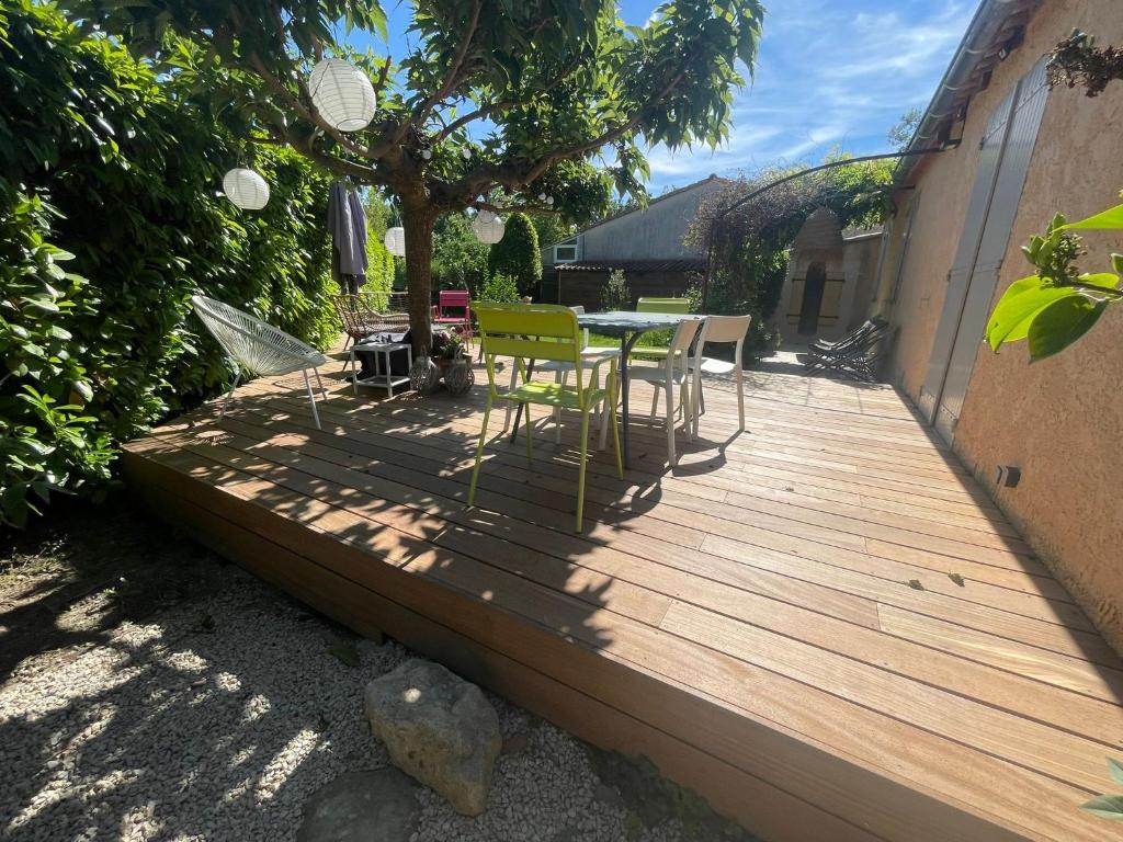 une terrasse en bois avec une table et des chaises dessus dans l'établissement Jolie maison de 95 m2 avec jardin proche Luberon, à Le Puy-Sainte-Réparade