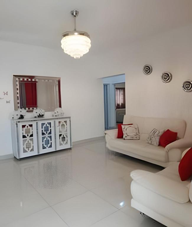 a white living room with a couch and a table at Casa cerca del aeropuerto. in Monte Llano