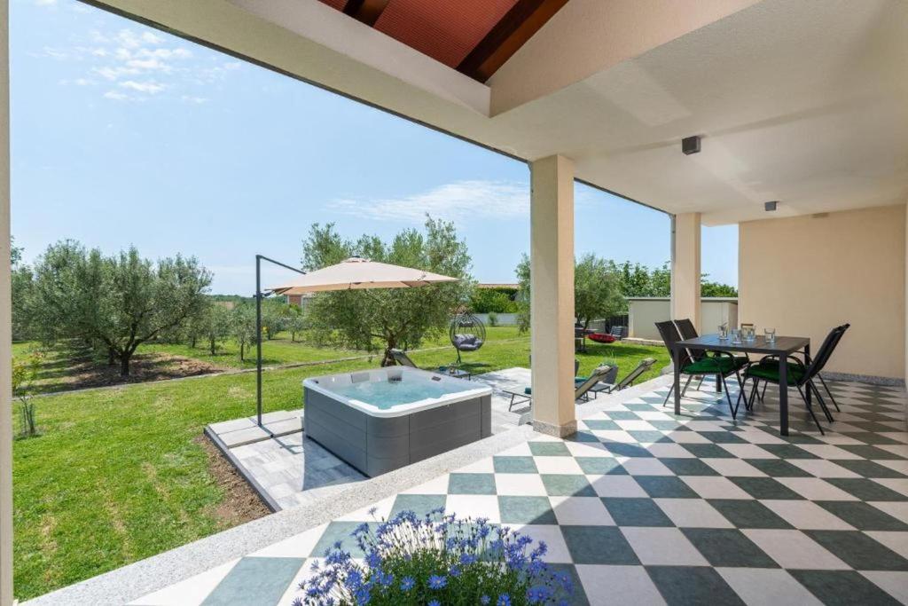 a patio with a hot tub and a table and chairs at Apartment Vista Olivo in Brtonigla