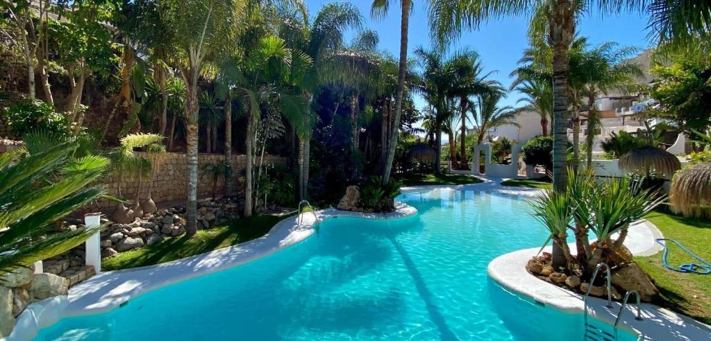 a swimming pool in a resort with palm trees at Apartment Rincón de Marinos in Almuñécar
