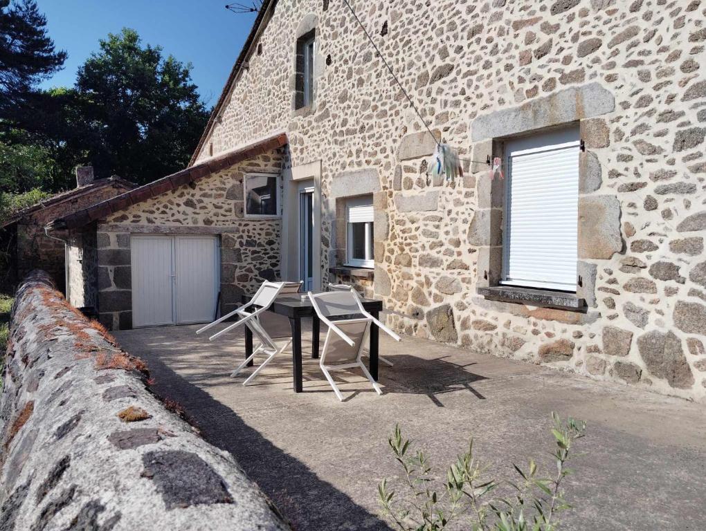 a stone house with two chairs and a table outside at Gîte et chambre d'hôtes Les Authentiques in Saint-Estèphe