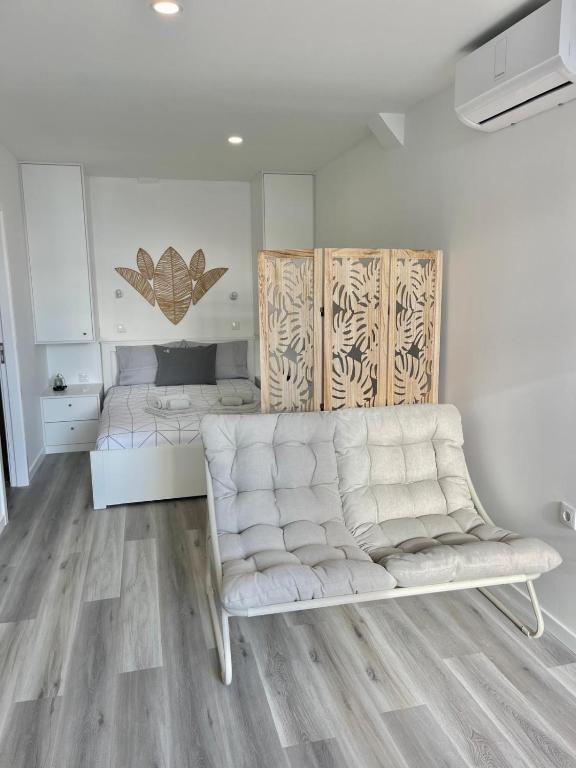 a living room with a white couch and a bed at Casa Pereira 5 in Ponta do Pargo