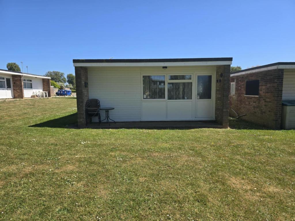 a house with a white door and a chair in a yard at 62 M&T Chalets , 2 bed detached chalet Florida holiday park Hemsby in Hemsby