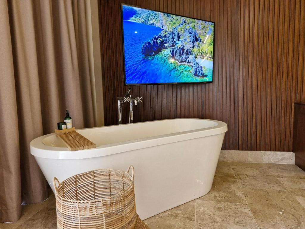 baño con bañera blanca y TV en la pared en Casa Cantaro Ocean View in La Amada Residences, en Cancún