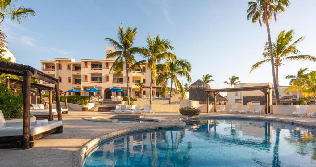 a resort swimming pool with palm trees and a building at Park Royal Homestay Los Cabos in San José del Cabo