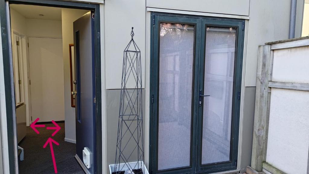 Una puerta de cristal con una flecha rosa al lado. en City Stay, en Christchurch