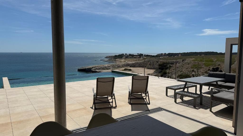 un patio avec une table et des chaises et l'océan dans l'établissement Vue sur mer EPOUSTOUFLANTE, à Sausset-les-Pins