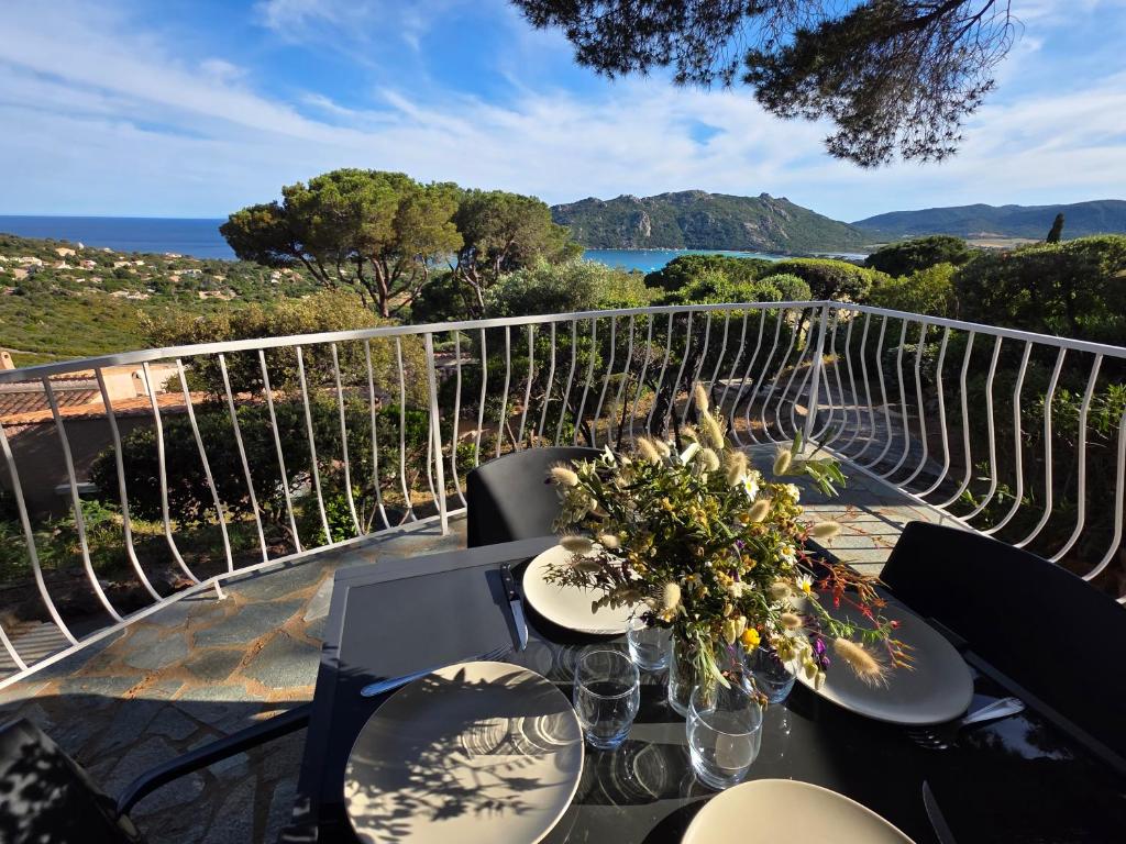 - une table avec des fleurs sur le balcon dans l'établissement Mini villa Paesolu, à Porto-Vecchio