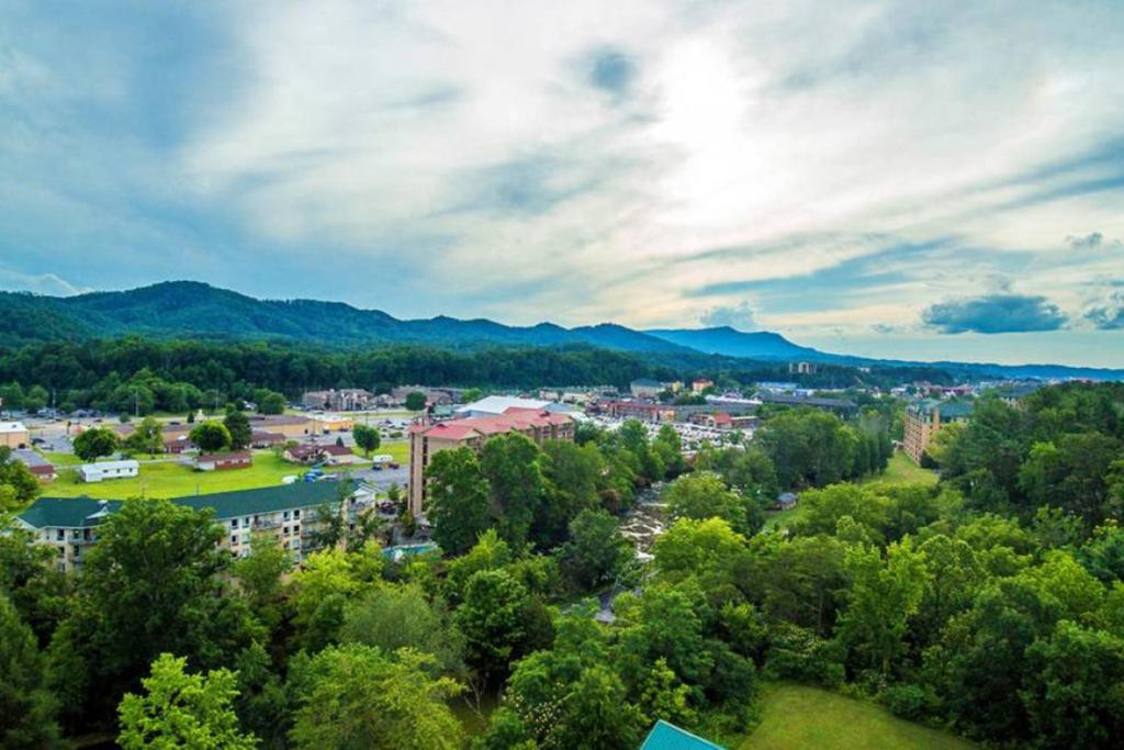 une vue aérienne sur une ville avec des arbres et des montagnes dans l'établissement The Bear Crossing by Venture Smoky Mountains, à Pigeon Forge
