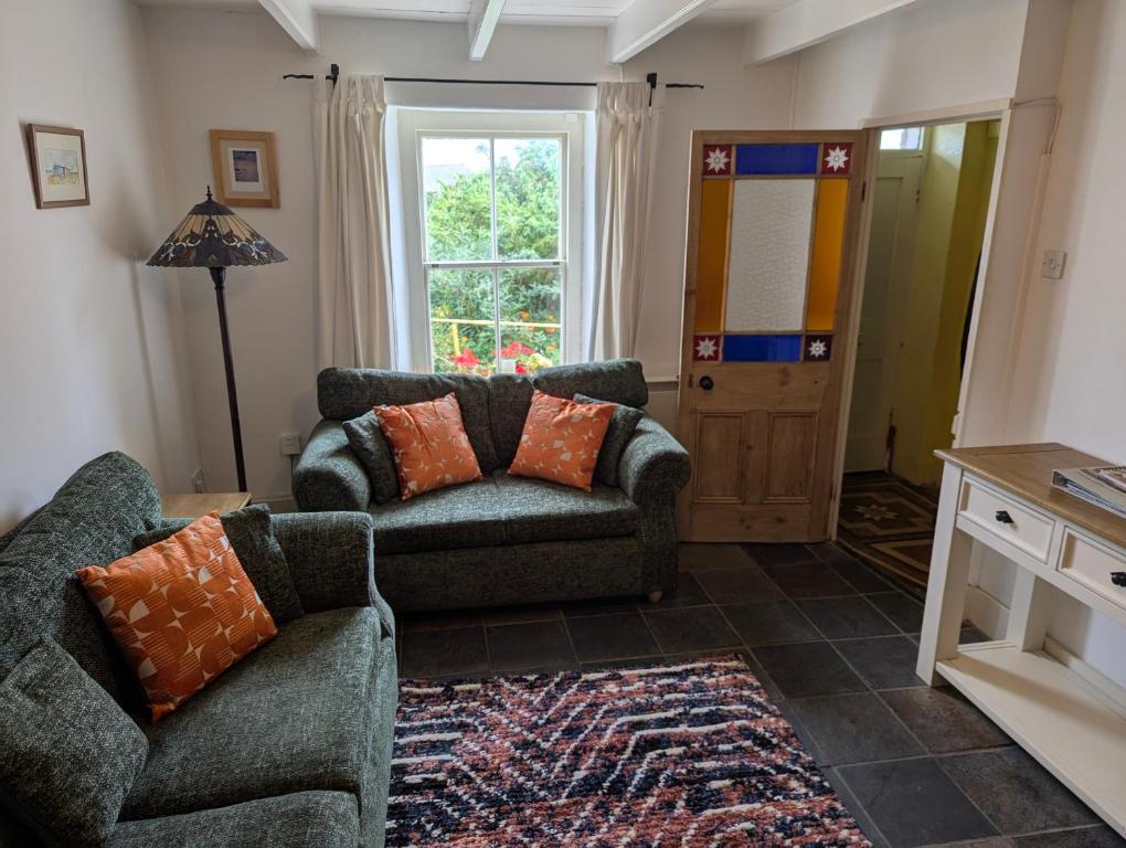 ein Wohnzimmer mit 2 Sofas und einem Fenster in der Unterkunft Traditional Fisherman's Cottage with 3 bedrooms in Mousehole