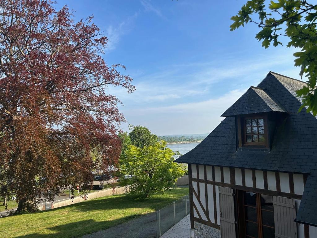 un bâtiment noir et blanc avec vue sur l'eau dans l'établissement Gite en bord de Seine, à Villequier