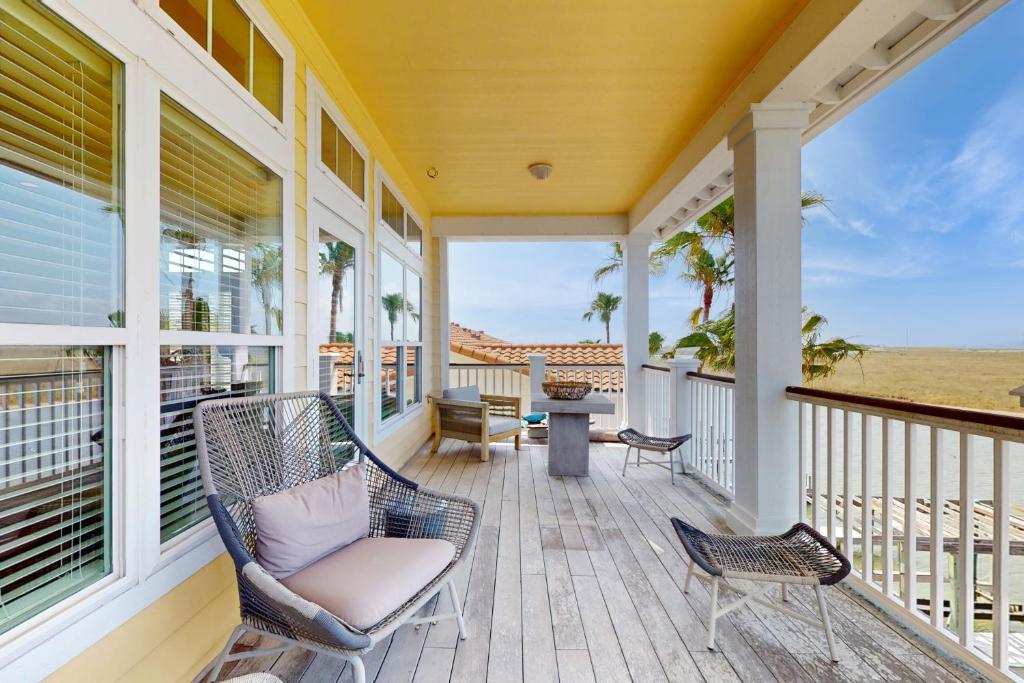 a porch with chairs and a table and the ocean at Cottage House #201 in Corpus Christi