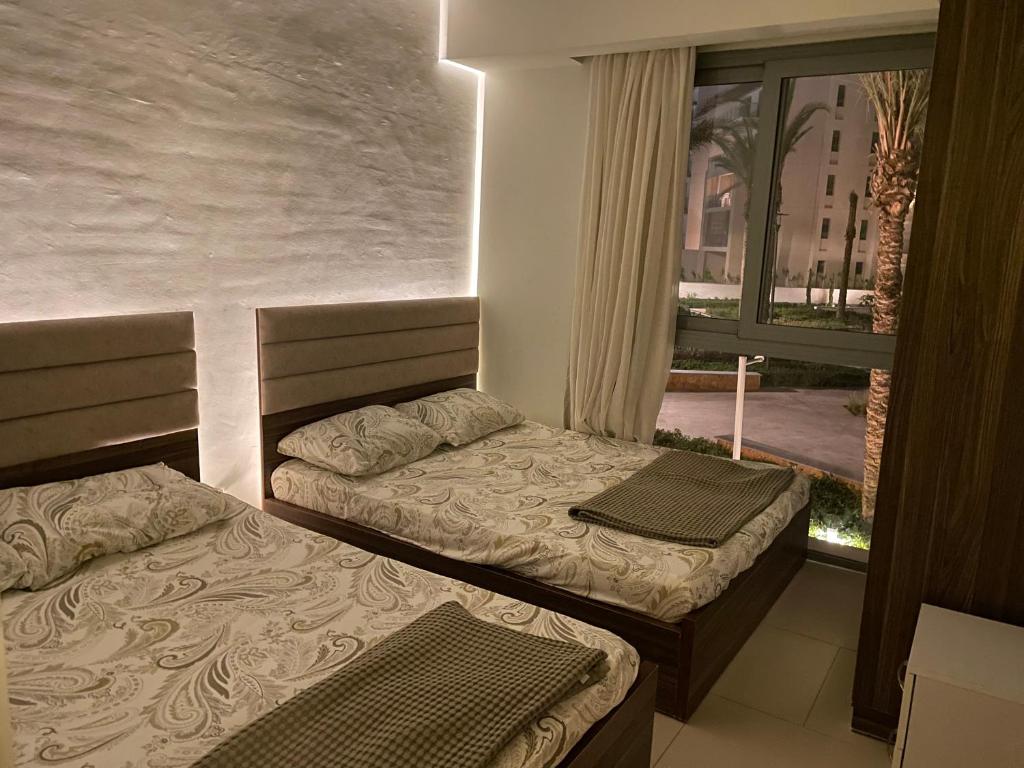 two beds in a room with a window at Apartment at Marassi in El Alamein