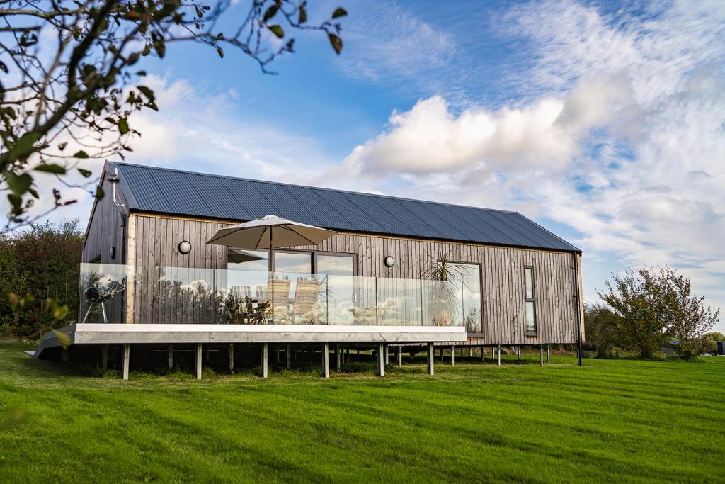 Six Road EndsにあるWillow Lodgeの野原に傘のある木造の建物