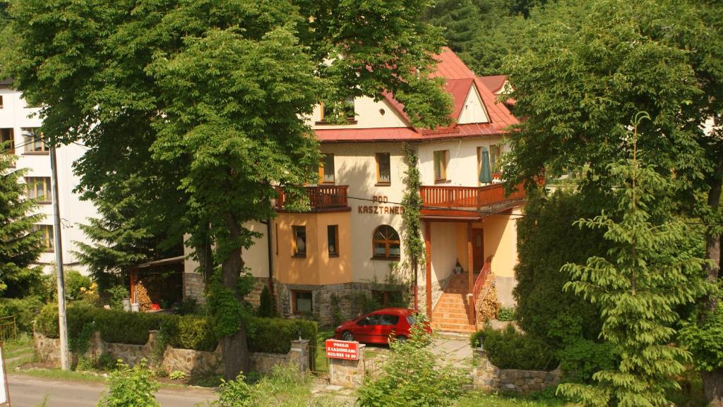 dom z czerwonym samochodem zaparkowanym przed nim w obiekcie Pod Kasztanem w Wiśle