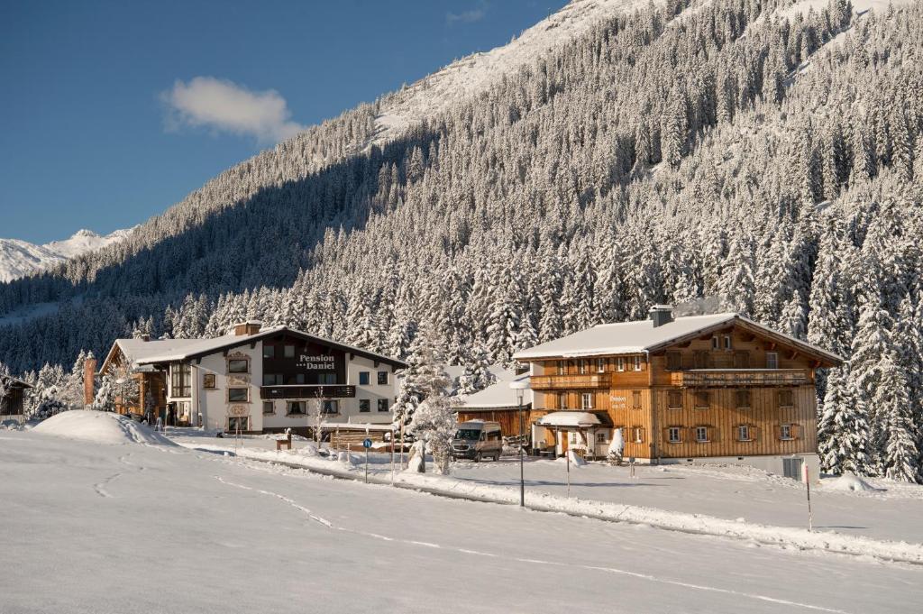 a couple of buildings in the snow next to a mountain at Pension Daniel in Lech am Arlberg