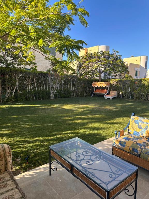 un patio avec une table en verre et une pelouse dans l'établissement Villa Hana green beach, à El Alamein