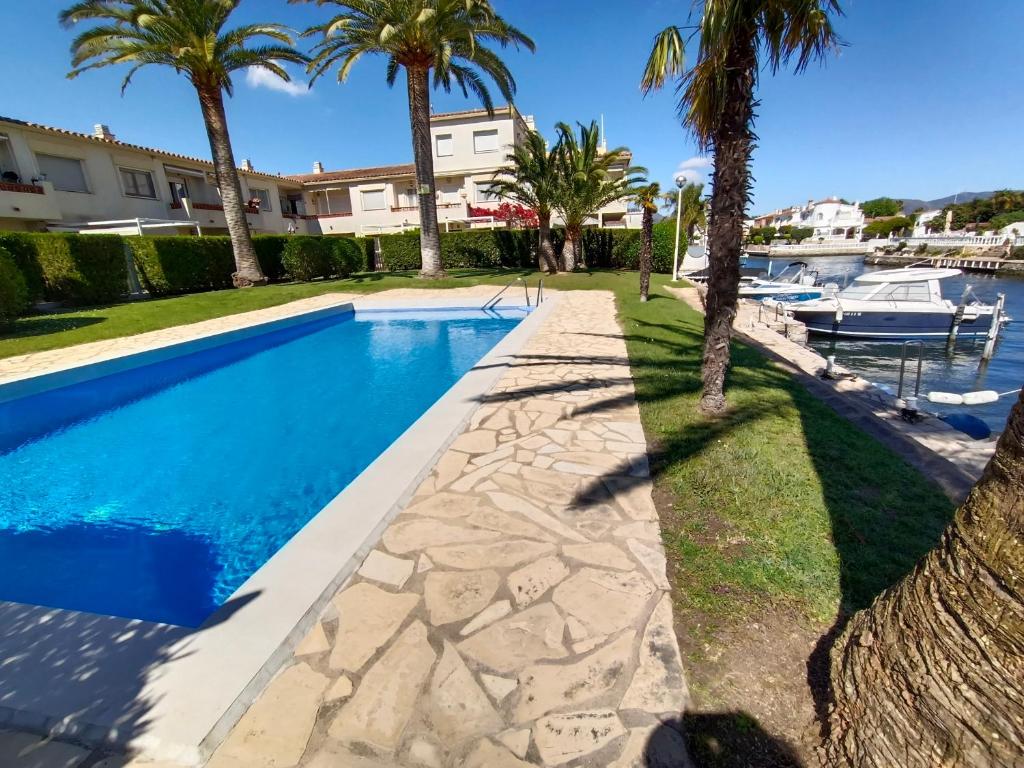 a swimming pool with palm trees next to a marina at Puerto Rico 6 in Empuriabrava