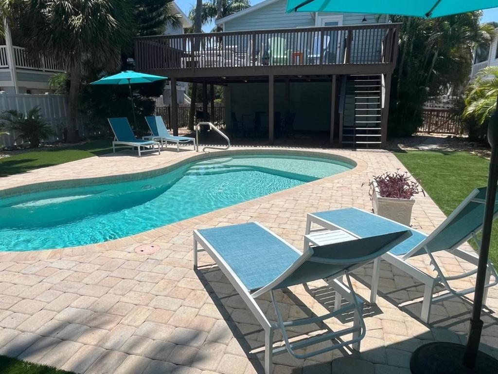 a swimming pool with two chairs and an umbrella at Canario Cottage Home in Anna Maria