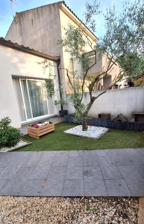une maison avec un arbre dans la cour dans l'établissement La Maison de Cathy, à Pérols