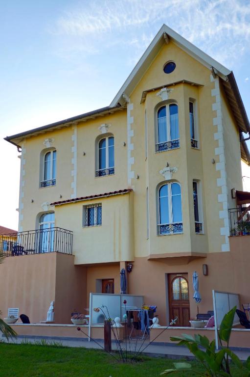 une grande maison jaune avec des fenêtres bleues dans l'établissement Très grand studio meublé - Juan les Pins - Logt4, à Antibes
