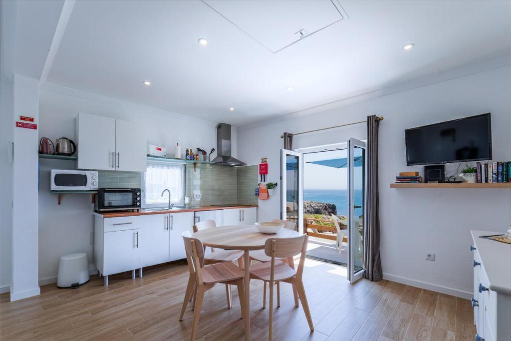 a kitchen and dining room with a table and a view of the ocean at CASA DA FALÉSIA 28 - Casa in Peniche