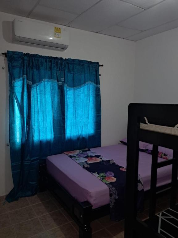 een slaapkamer met een paars bed en een blauw gordijn bij Hospedaje Mango y Mar in Coveñas