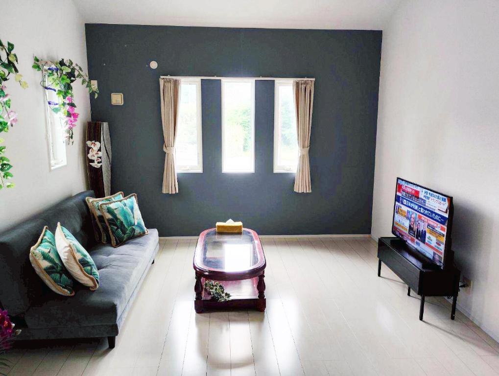 a living room with a couch and a flat screen tv at 水族館に近いゆったり別荘-Ent Terrace Okinawa in Motobu