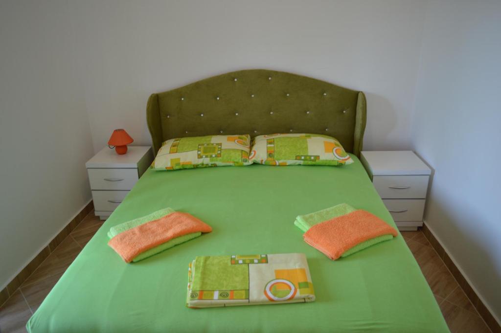 ein Bett mit grüner Bettwäsche und Kissen darauf in der Unterkunft Apartments Coso Zlatne njive bb in Kotor