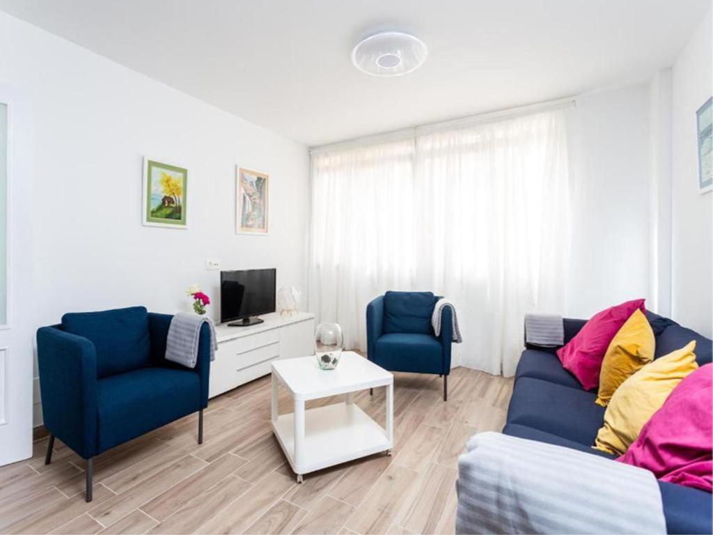 a living room with two blue chairs and a tv at Trip Medano England Centro in El Médano