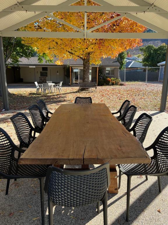 a wooden table with chairs under an umbrella at Willow Dene Holiday Apartments in Bright