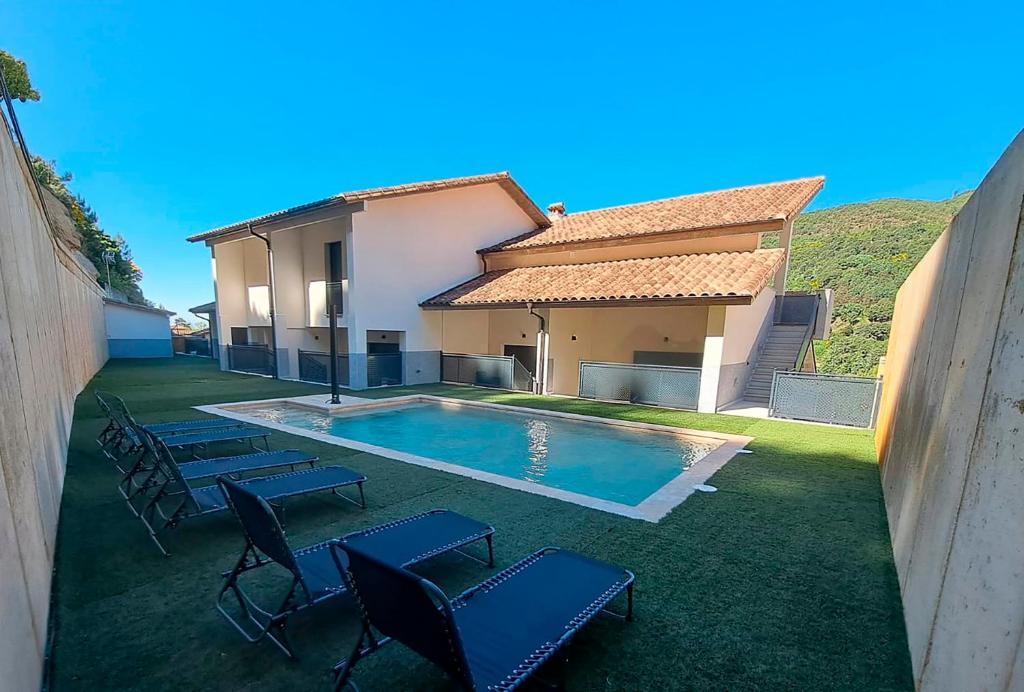 a backyard with a pool and chairs and a house at Apartamento La Monina CUEVAS DEL VALLE in Cuevas del Valle
