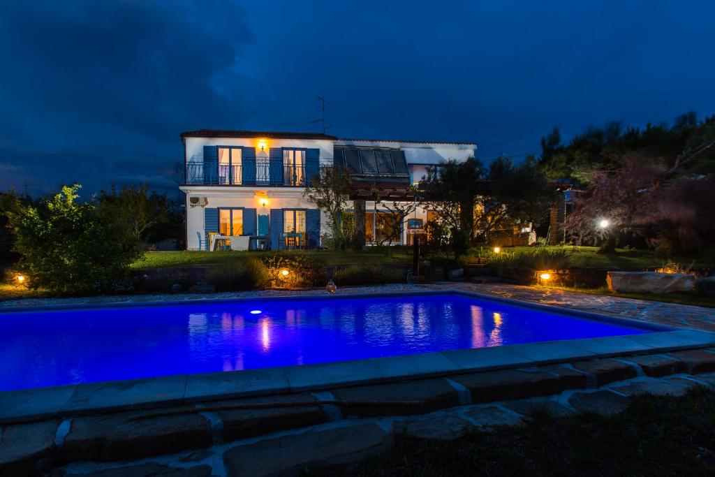 a swimming pool in front of a house at night at Apartments Novka in Izola