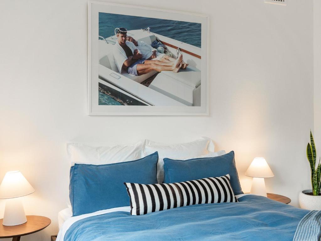 a bedroom with a bed and a picture of two people on a boat at The Fletcher Bondi in Sydney
