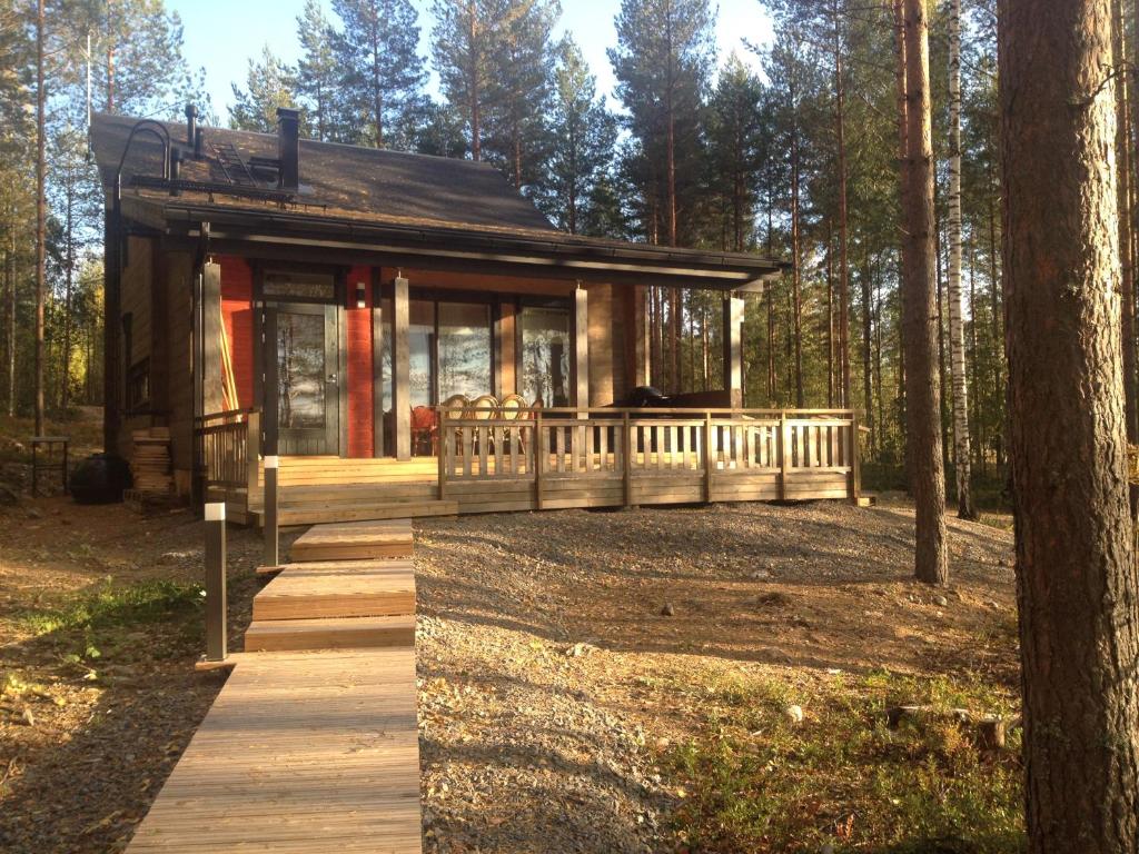 a small cabin in the woods with a wooden porch at Nestorinranta Villa in Lintusalo