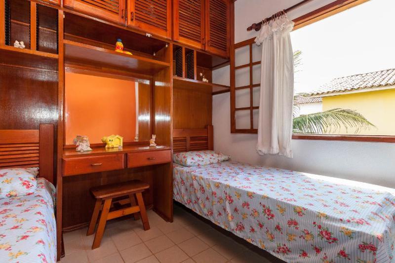 a bedroom with two beds and a desk and a window at Casa Duplex Praia Das Dunas in Cabo Frio