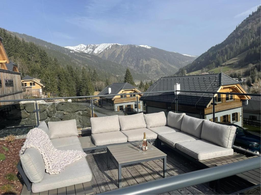 eine Couch und zwei Stühle auf einem Balkon mit Bergen in der Unterkunft Haus Ganbei in Donnersbachwald